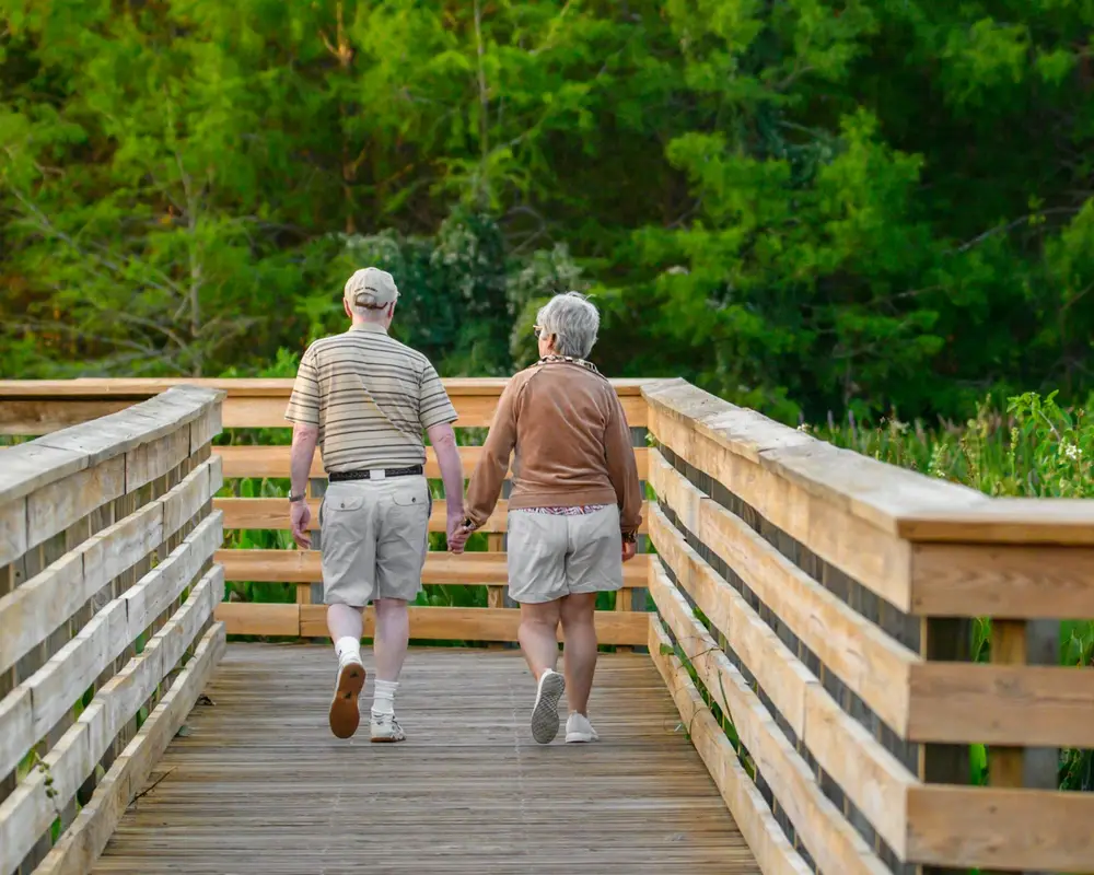 Pareja de adultos mayores caminando al aire libre en un entorno tranquilo